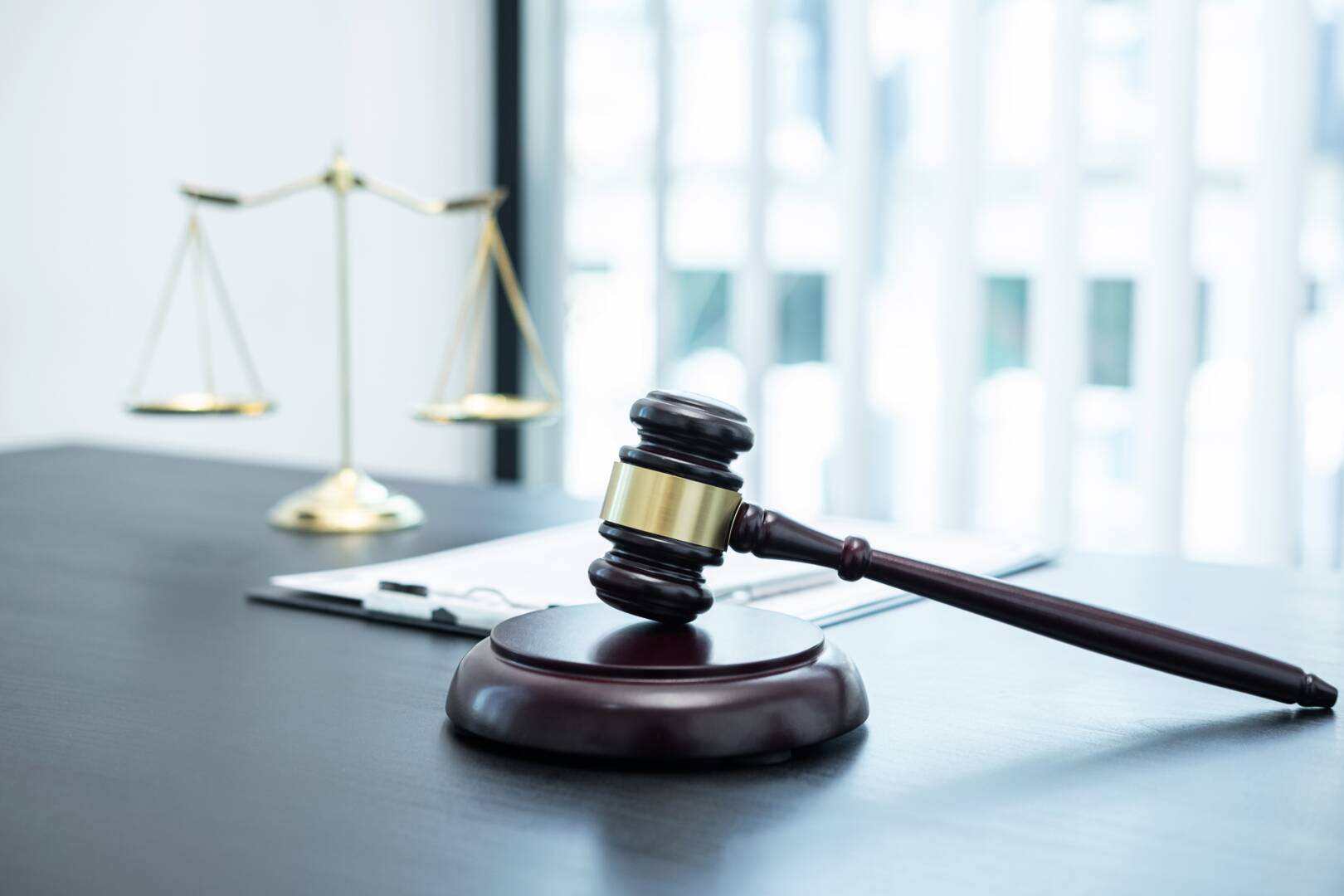 Judge gavel with Justice at law firm in background with legal case document contract, law and justice, attorney, lawsuit.